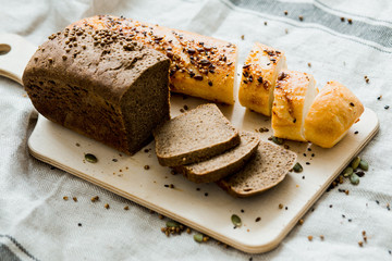 Fresh sliced bread on a wooden board on a grey cloth,