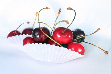 Berries of ripe red sweet cherry with horns in white paper substrates on white background