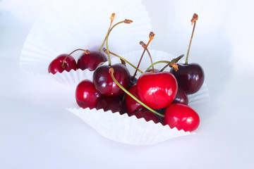 Berries of ripe red sweet cherry with horns in white paper substrates on white background