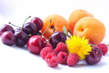 Berries of ripe red sweet cherry with horns, raspberries, apricots on a white background