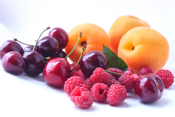 Berries of ripe red sweet cherry with horns, raspberries, apricots on a white background