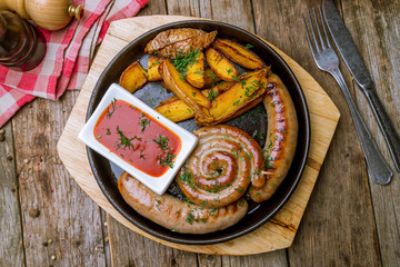 assorted sausages with sauces on wooden background