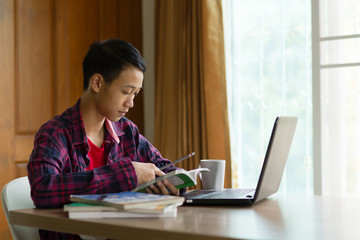 Young asia student is studying at home while use a laptop and mobile phone. online e-learning, stress student, education concept.