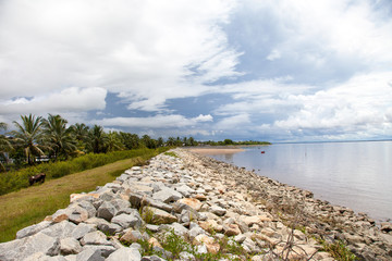 View of a dirt wall of boulders along the shore of the Atlantic ocean, Guyana on the background of...