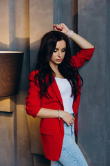 Photo session of a young brunette in jeans and a red jacket.