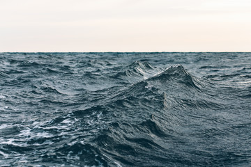 Naklejka na ściany i meble ripples on blue sea water with white foam , natural sea background