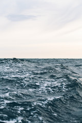 Obraz na płótnie Canvas ripples on blue sea water with white foam , natural sea background