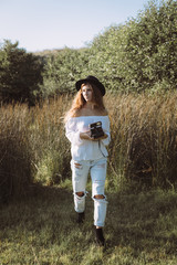 Hipster young girl taking a photo with an instant film retro camera. Artistic recreational hobby and leisure in nature concept. Asturias, Spain.