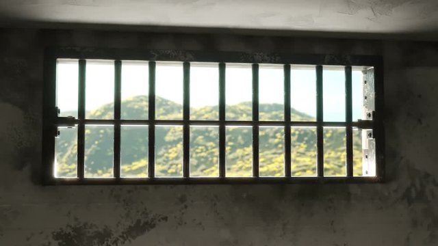 Animation of a grunge prison cell with landscape outside the barred-up window.