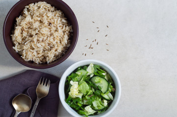 Bowl of rice with spices and vegetable salad on a gray background