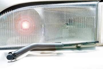 Close up of car headlights with wiper blades.