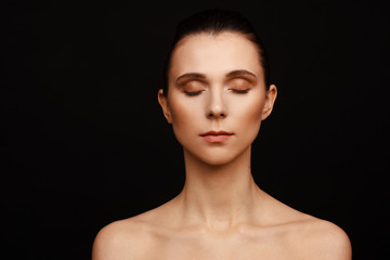 Portrait of a beautiful woman with collected hair and bare shoulders on a black background