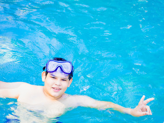 summer holidays and teenage concept - close up of male hand showing v-sign with fingers in the ocean transparent water.