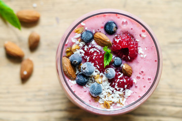 Raspberry and blackcurrant smoothie with almonds, granola and coconut topping