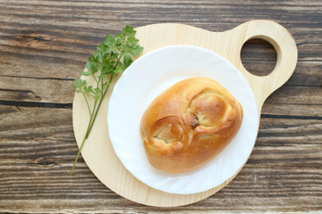 Tradisional russian Pie with onion and egg on a white plate on a round cutting board laying on a wooden table, top view, horizontal