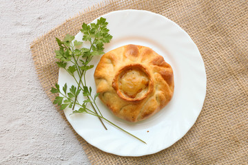 Traditional russian chicken pie kurnik on a plate laying on a table napkin on a grey background, top view, horizontal