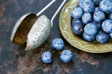 Nutritions, blueberries fruits with rustic tea strainer on a metal rusty background, healthy eating...