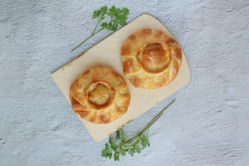 Two traditional russian chicken pies called kurnik on a wooden cutting board laying on a grey background, top view, horizontal © Lyudmila