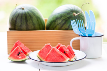 Watermelon cut into pieces in a white dish placed on a white wood floor,Summer fruit that is juicy