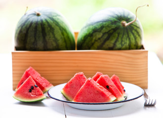 Watermelon cut into pieces in a white dish placed on a white wood floor,Summer fruit that is juicy