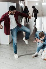 two students in jeans fighting in corridor in college