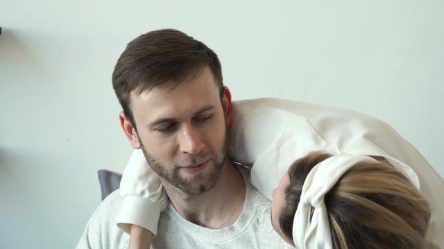 Happy caucasian beautiful young couple in love smile, hug and kis while sit on bed at home. Happy family concept