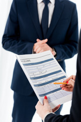 cropped view of woman holding resume and pencil near man with clenched hands