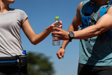 Runners couples give a bottle of water while he is running