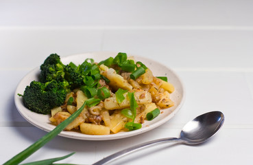  potatoes with chives and broccoli in a plate on white wooden background