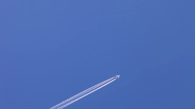 Aircraft contrail against clear blue sky.