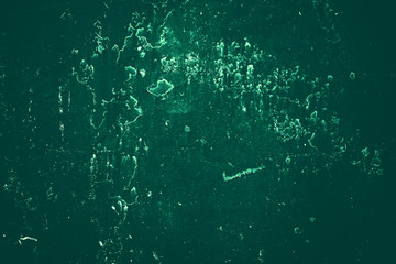 Vintage green background. Rough painted wall of emerald color. Imperfect plane of virid colored. Uneven old decorative toned backdrop of green tint. Texture of emerald hue. Ornamental stony surface.