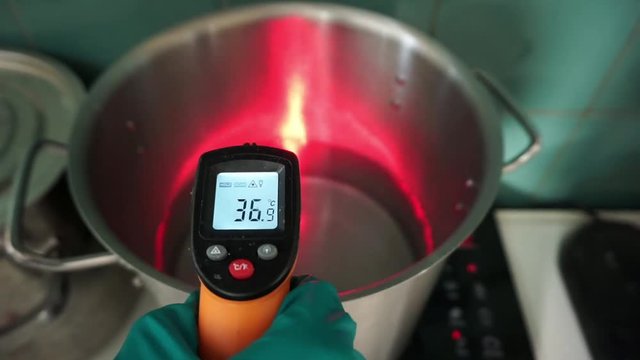 The scientist measures the temperature using a remote infrared pyrometer