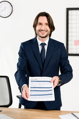 handsome recruiter smiling while holding resume in hands