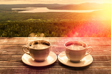 Two cups of hot coffee, on the table against the landscape, vegetation. date, travel, vacation. tourism.