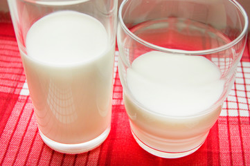 Two glasses of milk on a red checkered cloth, healthy food concept