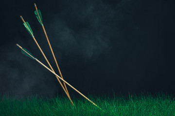 Three wooden arrows in the grass. Beautiful smog background. Medieval weapons handmade.