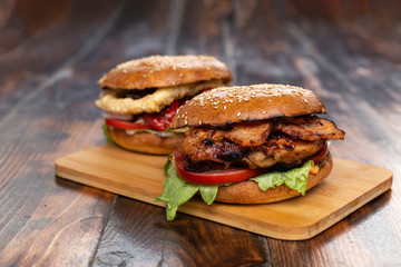 Two homemade beef burgers with fried potato on wooden cutting board