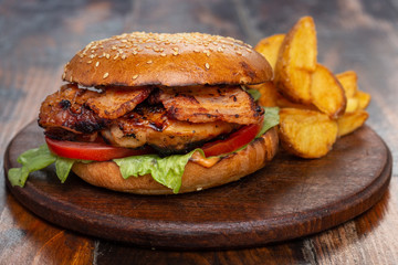 very big fat classic american hamburger with french fries on a wooden board
