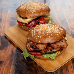 Two homemade beef burgers with fried potato on wooden cutting board
