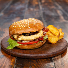 very big fat classic american hamburger with french fries on a wooden board
