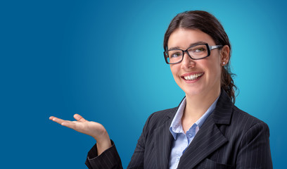 smiling businesswoman showing empty hand isolated in blue background