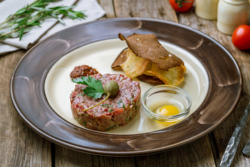 Tartare from beef on wooden background