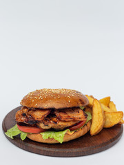 Classic american hamburger on a wooden board with fried potatoes, white background