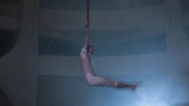Professional artist circus performer showing awesome stunt on a stage, smoke around