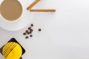 White cup of hot coffee and Cinnamon sticks and Mango sweet cake.