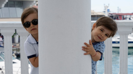 Modern four-year-old twin brothers posing on the marina.