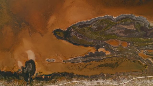 Amazing view of picturesque dark island with brown earth and yellow reservoirs with dirty water, covered by tropical plants. Shot. View from above of strange island