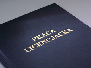 Closeup of a cover of Polish bachelor dissertation. Gold lettering on navy blue cover.
