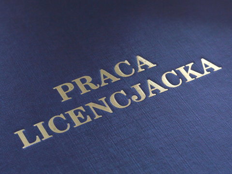 Closeup of a cover of Polish bachelor dissertation. Gold lettering on navy blue cover.