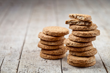 Two stacks of fresh baked oat cookies on rustic wooden table background.